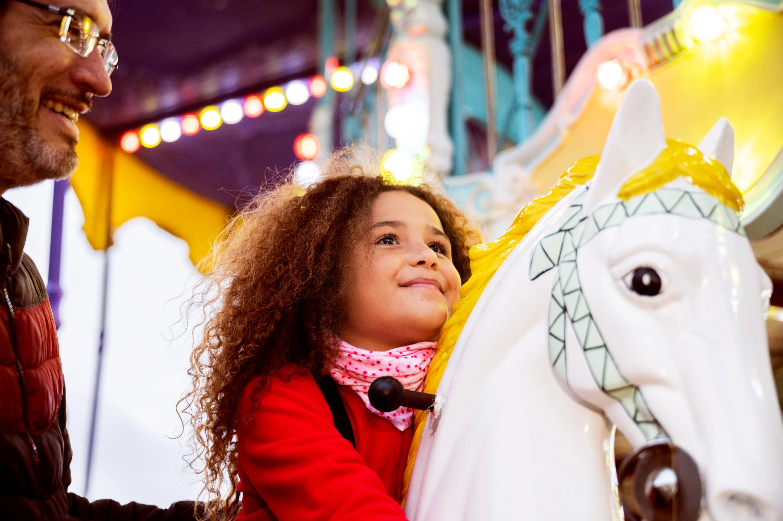 Blij jong meisje op een paard van eeen draaimolen